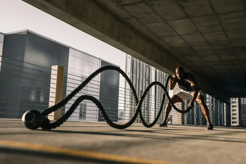 Hombre entrenando con cuerdas de batalla