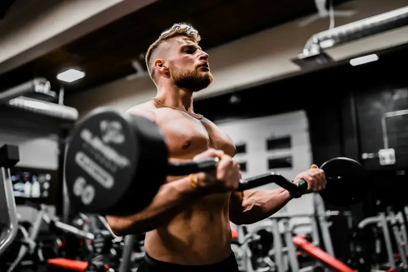 Hombre haciendo curl de bíceps con barra